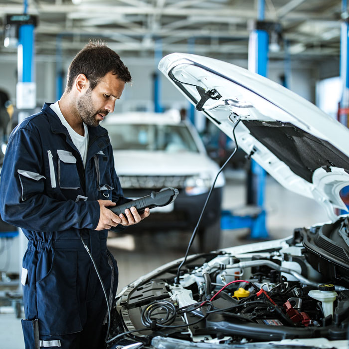 mechanic doing diagnostic work under hood of car