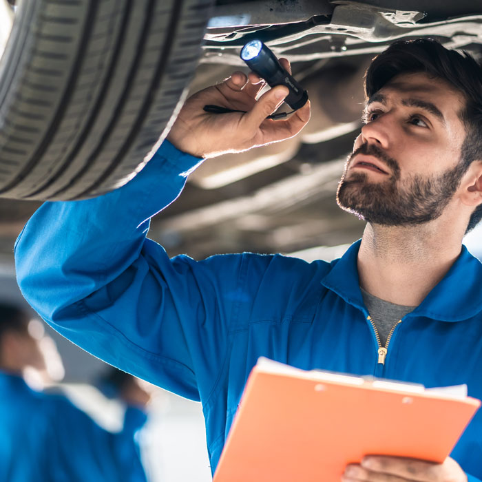 mechanic inspecting under car by tire