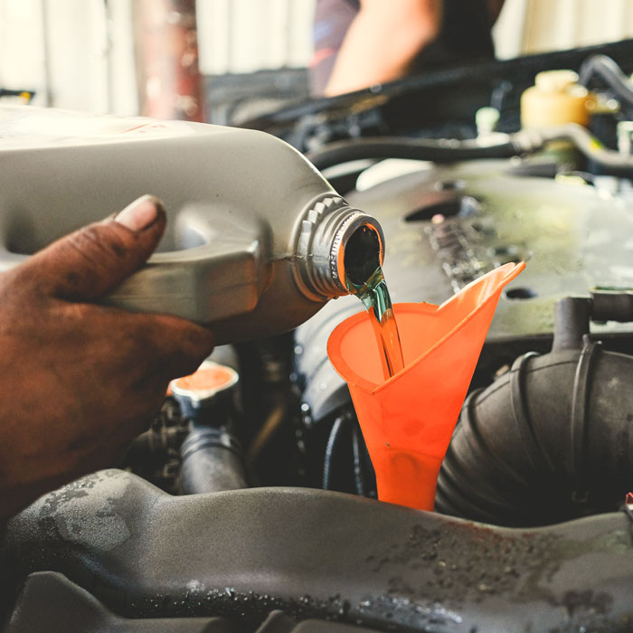 mechanic adding fluids to car