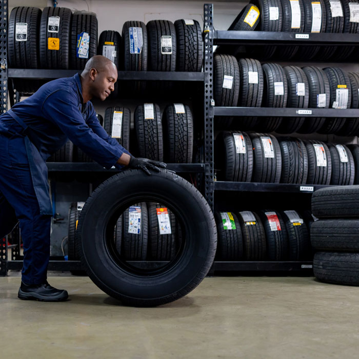 mechanic rolling tire across shop floor