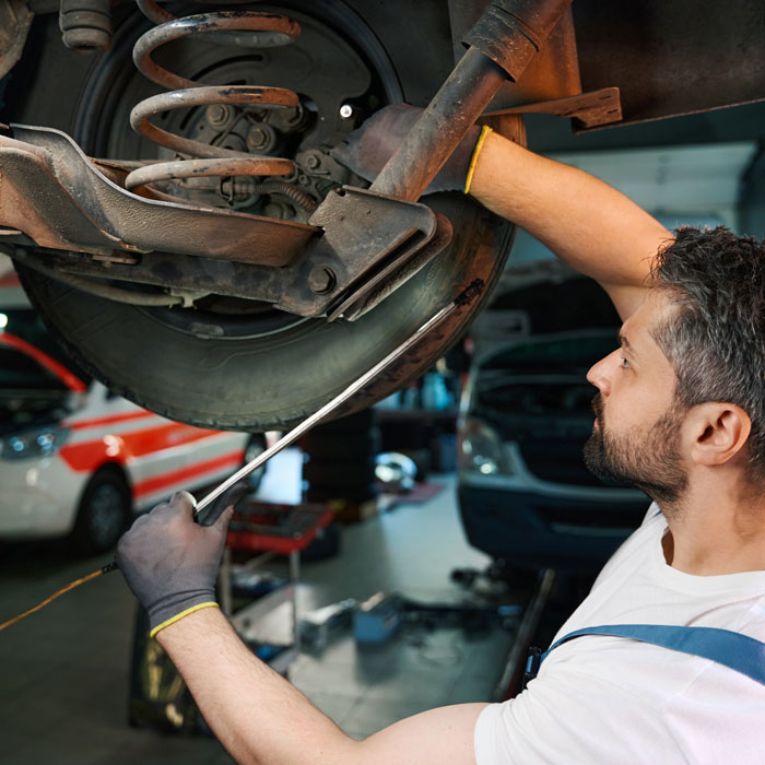 mechanic looking under car near tire