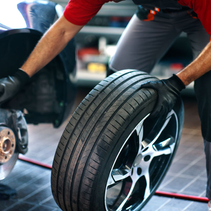 mechanic about to attach wheel to car