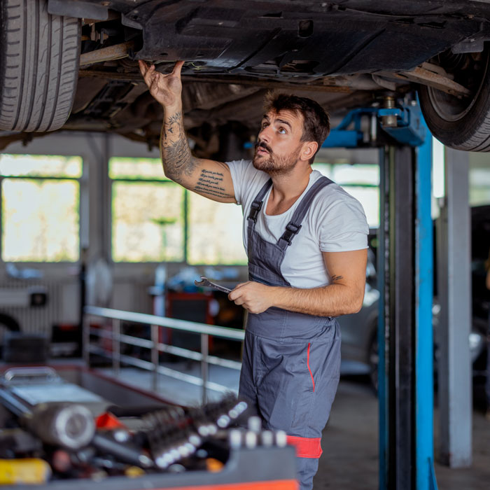 mechanic inspecting underside of car