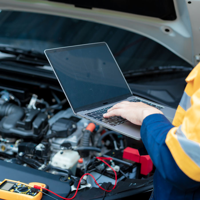 mechanic with computer hooked up to car engine