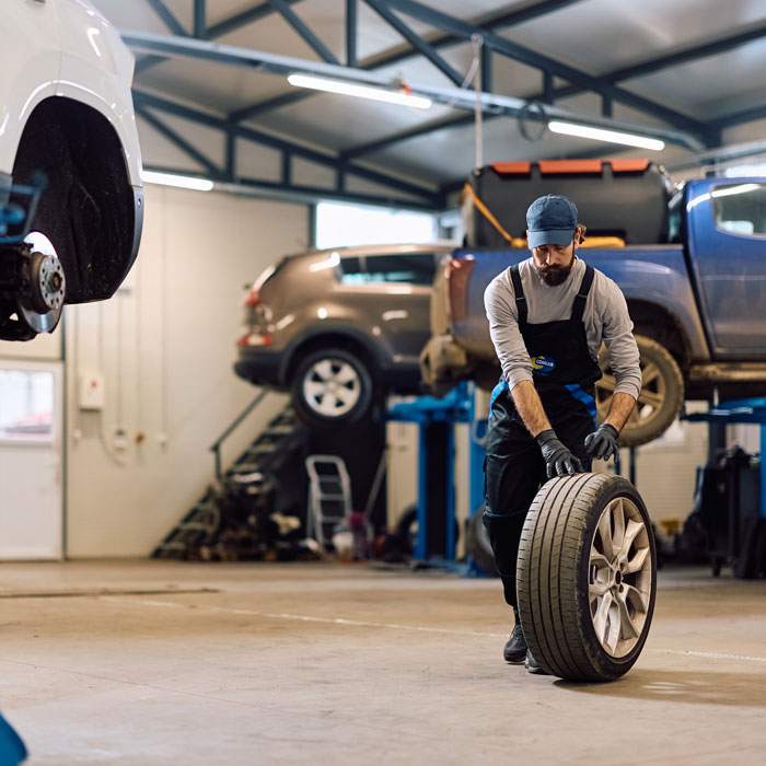 mechanic rolling tire to car