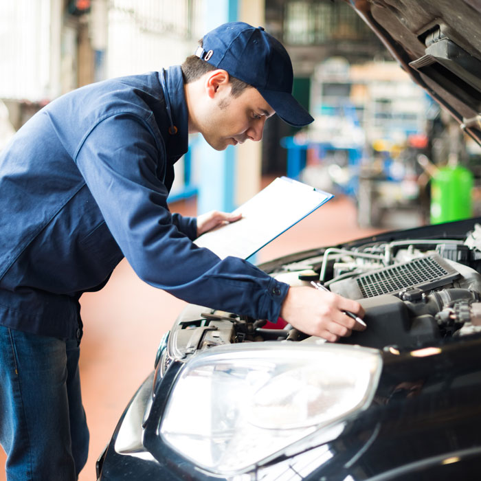 mechanic inspecting under hood of car