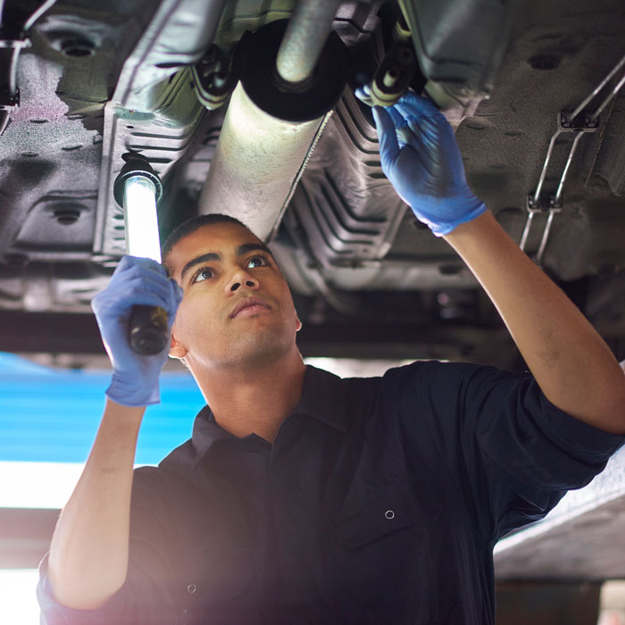 mechanic inspecting underside of car
